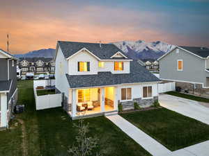 Back of property at dusk with central AC, a mountain view, stone siding, and a fenced backyard