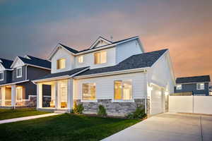 View of front of property featuring a front lawn, driveway, stone siding, fence, and a garage