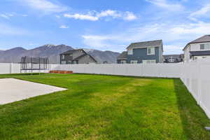 View of yard with a residential view, a fenced backyard, a mountain view, a trampoline, and a patio area