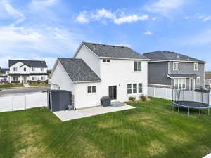 Rear view of property with a fenced backyard, a residential view, a patio, and a trampoline