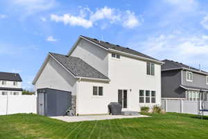 Back of house featuring a trampoline, fence, a yard, a patio, and stucco siding