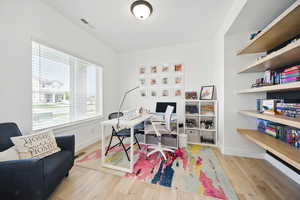 Home office with baseboards, wood finished floors, and visible vents