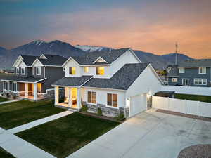 Modern farmhouse style home with a mountain view, stone siding, fence, covered porch, and a garage