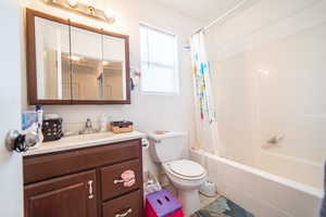 Full bath with tile patterned floors, shower / bath combo with shower curtain, vanity, and toilet