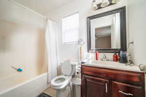 Full bath with shower / bath combination with curtain, tile patterned floors, vanity, and toilet