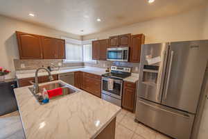 Kitchen with a sink, tasteful backsplash, recessed lighting, appliances with stainless steel finishes, and light tile patterned floors