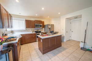 Kitchen with light countertops, appliances with stainless steel finishes, decorative backsplash, and light tile patterned floors