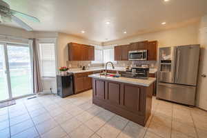 Kitchen featuring a ceiling fan, decorative backsplash, light tile patterned floors, light countertops, and appliances with stainless steel finishes