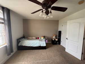 Carpeted bedroom with ceiling fan and baseboards