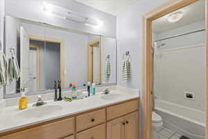 Full bath featuring toilet, tile patterned flooring, a sink, and double vanity