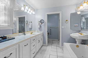 Bathroom with a bathtub, a shower with door, a sink, and baseboards
