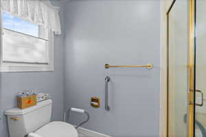 Full bath featuring baseboards, toilet, and a stall shower