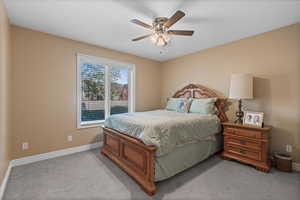 Bedroom featuring light carpet, a ceiling fan, and baseboards