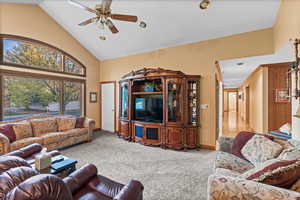 Carpeted living area featuring baseboards, a ceiling fan, and high vaulted ceiling