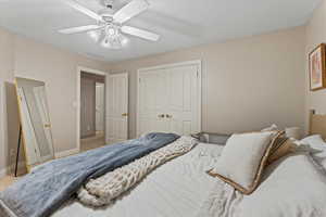 Carpeted bedroom with a closet, baseboards, and ceiling fan