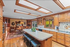 Kitchen featuring light countertops, backsplash, a sink, light wood-style floors, and black appliances