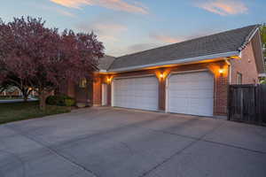 View of front of property featuring an attached garage, fence, brick siding, and concrete driveway