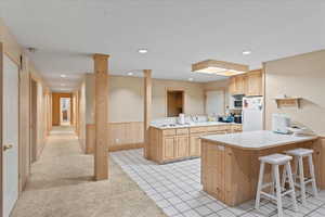 Kitchen with a peninsula, freestanding refrigerator, light brown cabinetry, and a sink