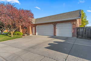View of front of house with concrete driveway, brick siding, fence, and a garage
