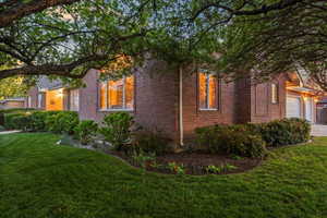 View of property exterior with brick siding, a lawn, concrete driveway, and a garage