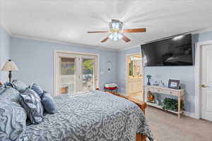 Bedroom featuring a textured ceiling, ceiling fan, carpet, ornamental molding, and access to exterior