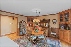 Dining room with light wood-style flooring and crown molding