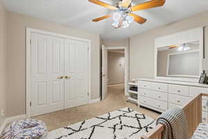 Bedroom featuring light colored carpet, ceiling fan, baseboards, and a closet