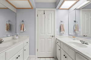 Bathroom with two vanities, tile patterned floors, and a sink