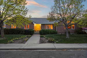 Ranch-style house featuring brick siding, a lawn, and a tile roof