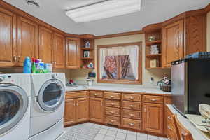 Washroom with a sink, washer and clothes dryer, visible vents, cabinet space, and light tile patterned floors