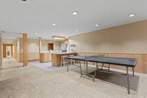Recreation room with light carpet, a wainscoted wall, wooden walls, and recessed lighting