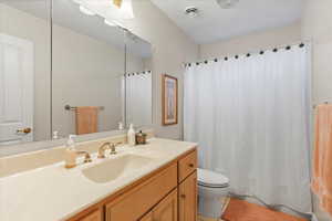 Bathroom with shower / tub combo, toilet, vanity, and tile patterned floors