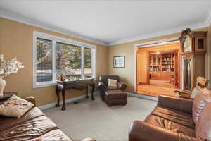 Living room featuring baseboards, visible vents, crown molding, and light colored carpet