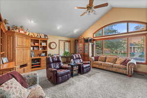 Living area featuring carpet, visible vents, a ceiling fan, and high vaulted ceiling
