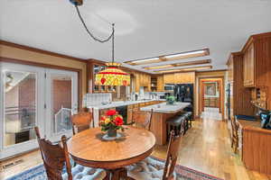Dining room with light wood-type flooring, visible vents, a textured ceiling, and crown molding