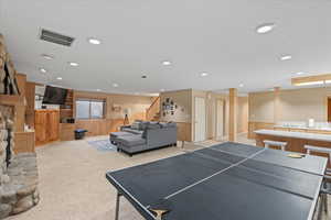 Recreation room featuring wainscoting, wooden walls, light colored carpet, and visible vents