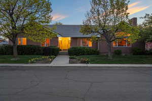 View of front of home with brick siding, a tile roof, a chimney, and a front lawn