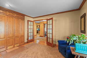 Interior space featuring light colored carpet, crown molding, baseboards, and french doors