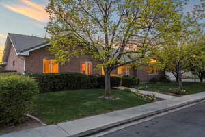 View of property hidden behind natural elements with brick siding and a yard