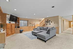 Living area with wainscoting, light carpet, wood walls, and stairway