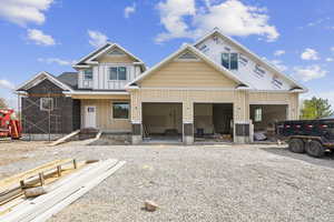 View of front of home with board and batten siding, gravel driveway, and a garage