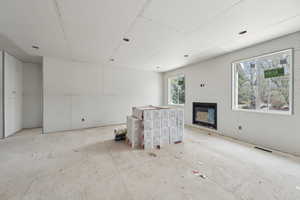 Unfurnished living room with a glass covered fireplace and visible vents
