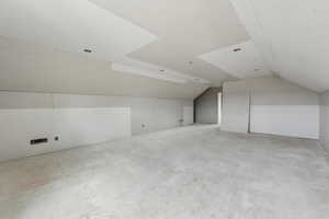 Bonus room featuring concrete floors and vaulted ceiling