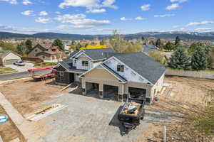 View of front of house with fence, a shingled roof, driveway, and a mountain view