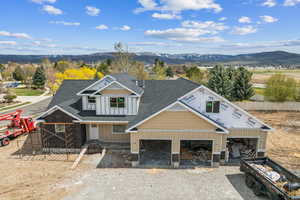 View of front of home featuring board and batten siding, driveway, a shingled roof, and a mountain view