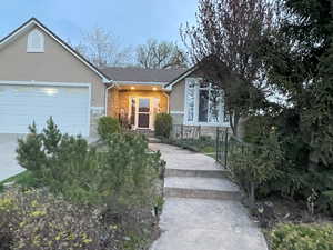 View of front of property featuring stucco siding, an attached garage, driveway, and stone siding