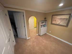 Interior space featuring recessed lighting, arched walkways, crown molding, baseboards, and light colored carpet
