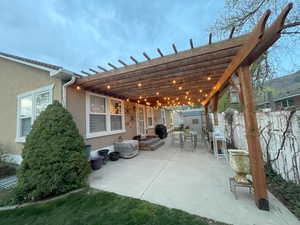 View of patio with an outdoor structure, a pergola, fence, and a storage unit