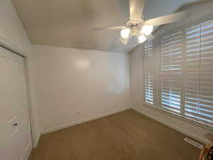Unfurnished bedroom featuring a closet, ceiling fan, baseboards, lofted ceiling, and visible vents