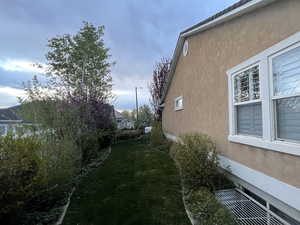 View of side of home with a yard and stucco siding